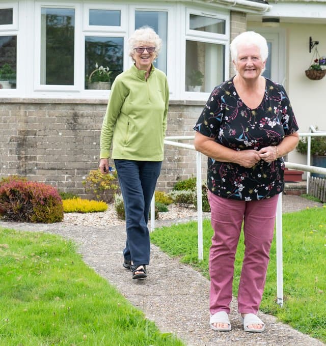 Older ladies walking outside house