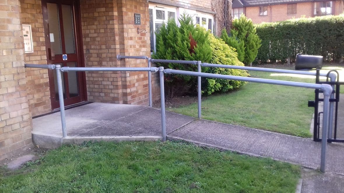 wheelchair accessible path with rails and space to park outside without blocking entrance